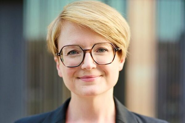 Junge Frau mit roten, kurzen Haaren und Brille