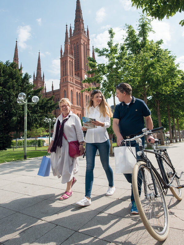 Two women and a man after shopping. A church in the background.
