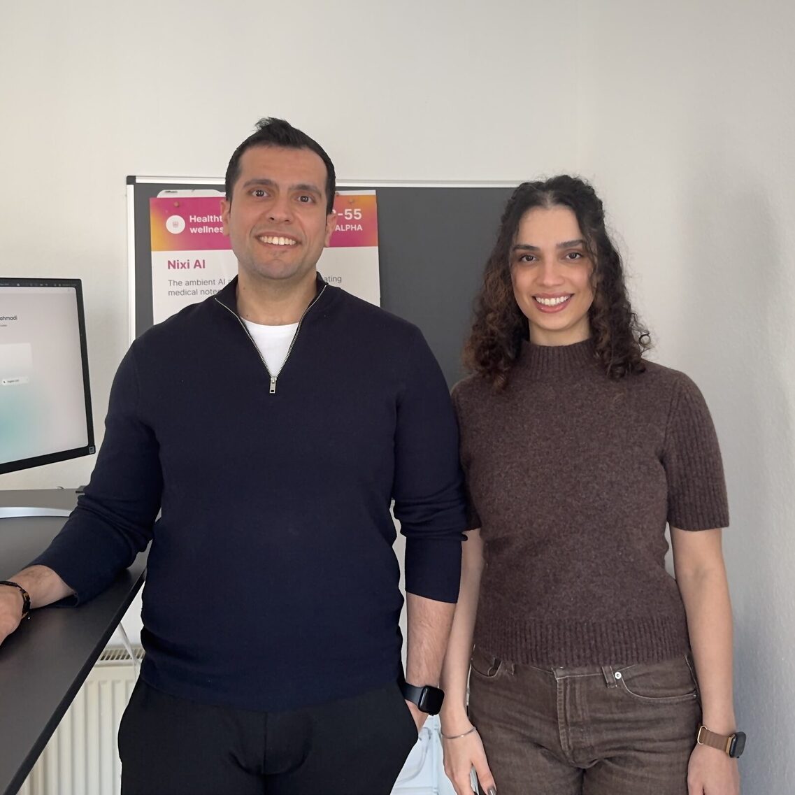 Man in blue shirt and woman in brown shirt looking into camera