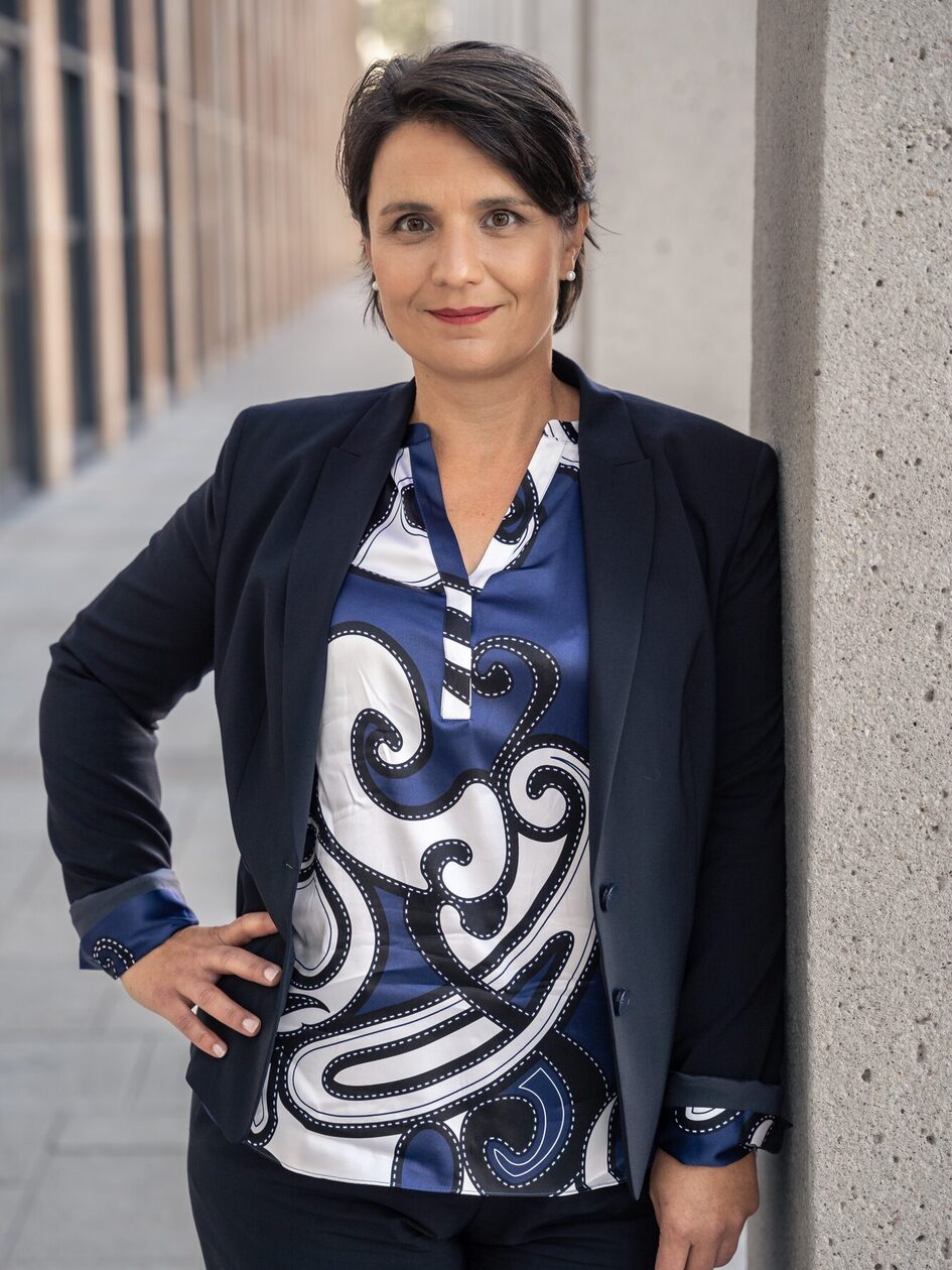 Frau posiert im Businessdress an einer Betonsäule