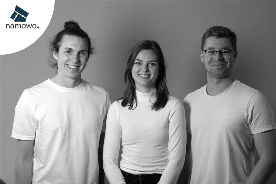 zwei Männer und eine Frau mit weißen Oberteilen lächeln in die Kamera, in der oberen linken Ecke ist das Logo der Firma "namowo" zu sehen. Das Bild ist in sepia.