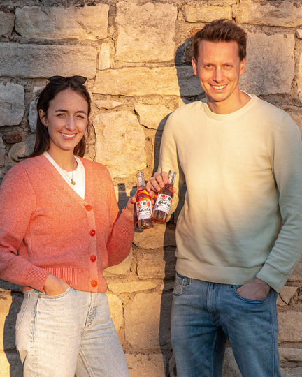 Mann und Frau vor Mauer mit zwei Flaschen in der Hand