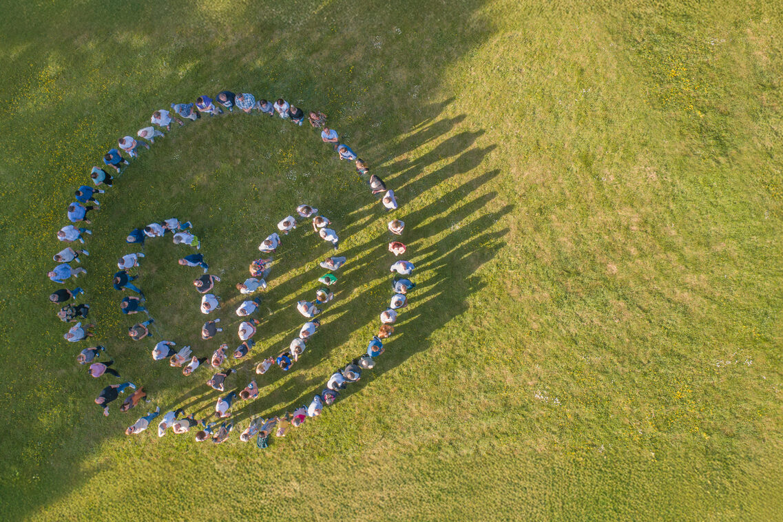 Logo horticultural insurance from the air formed with people on lawns.