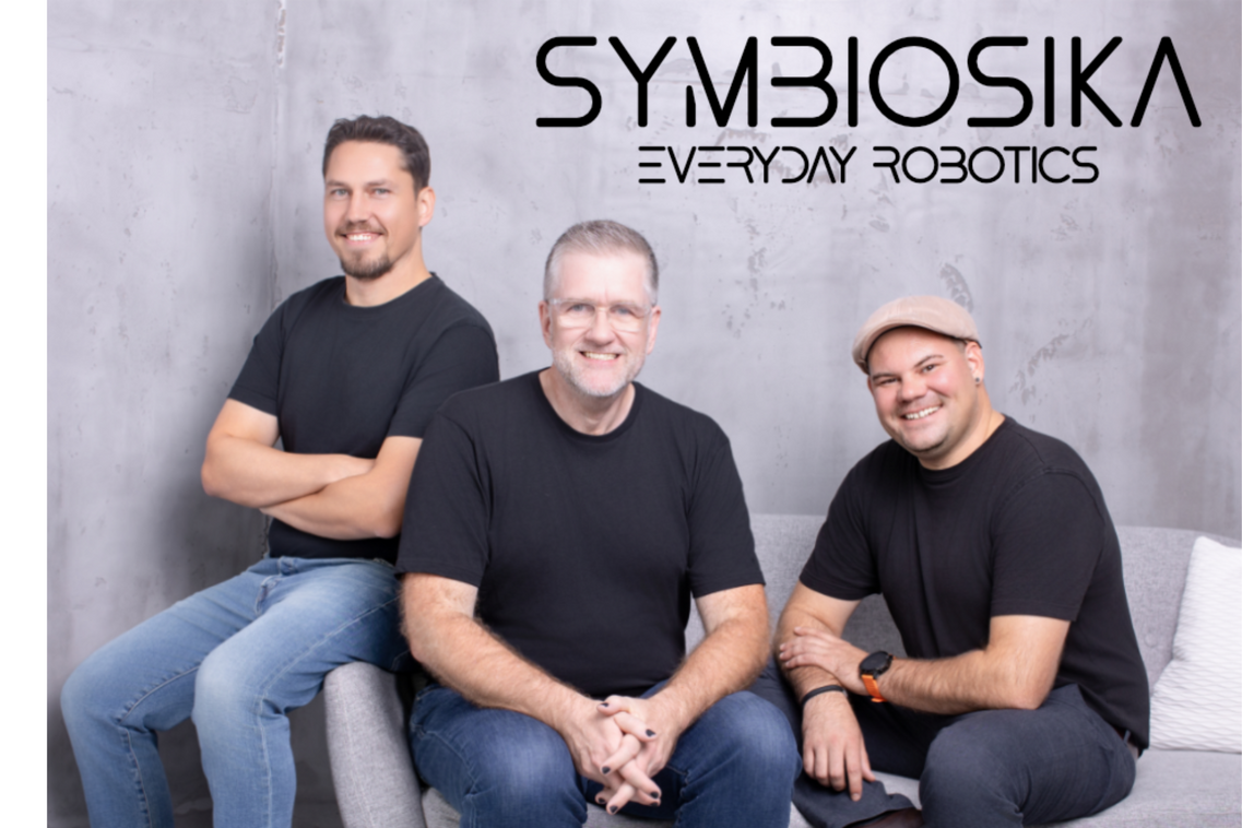 Drei Männer sitzen auf einer Couch und schauen freundlich in die Kamera.