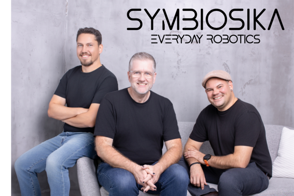 Drei Männer sitzen auf einer Couch und schauen freundlich in die Kamera.